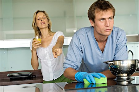 scolding - Smiling woman pointing at angry man holding sponge Stock Photo - Premium Royalty-Free, Code: 6108-05858959