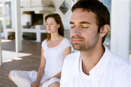 Couple sitting cross-legged on wooden terrace, eyes closed Stock Photo - Premium Royalty-Free, Code: 6108-05858971