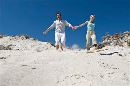 running sand dune - Couple holding hands, running down sand dune Stock Photo - Premium Royalty-Free, Code: 6108-05858980