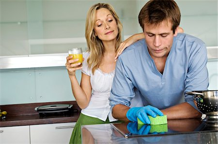 Young woman laughing at man using sponge in kitchen Foto de stock - Sin royalties Premium, Código: 6108-05858987