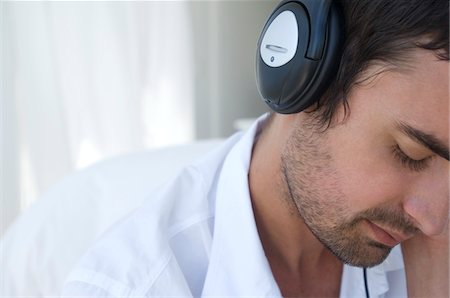 simsearch:6108-05856112,k - Portrait of young man listening to music with headphones Foto de stock - Royalty Free Premium, Número: 6108-05859047