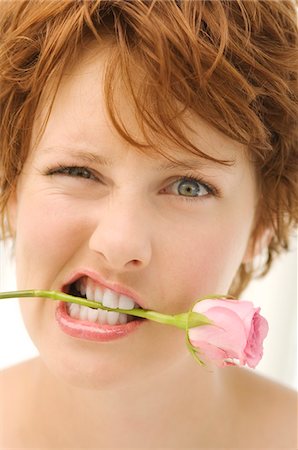 Portrait of young woman with rose between teeth Stock Photo - Premium Royalty-Free, Code: 6108-05859080