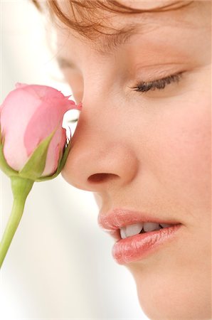 Portrait of young woman with rose in front of face, eyes closed Stock Photo - Premium Royalty-Free, Code: 6108-05859148