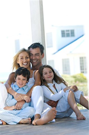 simsearch:6108-05857785,k - Couple and two children smiling for the camera, sitting on wooden terrace Stock Photo - Premium Royalty-Free, Code: 6108-05859155