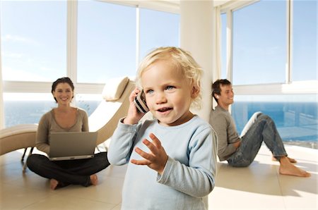 room dada - Little girl using mobile phone, parents in background Stock Photo - Premium Royalty-Free, Code: 6108-05859158