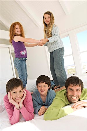 famiglia numerosa - Smiling couple and three children on bed Fotografie stock - Premium Royalty-Free, Codice: 6108-05859165