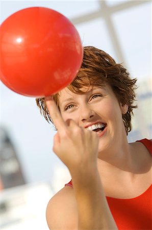 Portrait de jeune femme ballon rouge sur son doigt d'équilibrage Photographie de stock - Premium Libres de Droits, Code: 6108-05859119