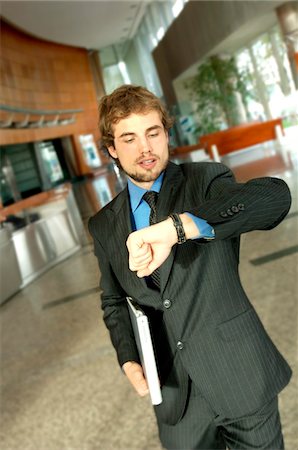 simsearch:6108-05859384,k - Young businessman looking at wristwatch Stock Photo - Premium Royalty-Free, Code: 6108-05859347