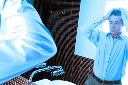 sad adult looking at camera - Reflection of mid adult man standing in front of mirror in washroom Stock Photo - Premium Royalty-Free, Code: 6108-05859367