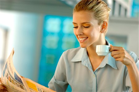 Businesswoman reading newspaper, smiling Stock Photo - Premium Royalty-Free, Code: 6108-05859307