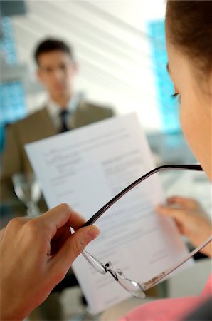 documents office - Businesswoman reading paper with colleague in background Stock Photo - Premium Royalty-Free, Code: 6108-05859444