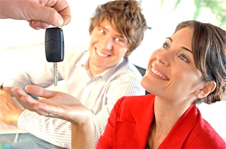 Car dealer handing car key to customer, smiling Stock Photo - Premium Royalty-Free, Code: 6108-05859474