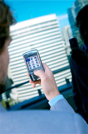 Businessman using mobile phone, rear view Stock Photo - Premium Royalty-Free, Code: 6108-05859481