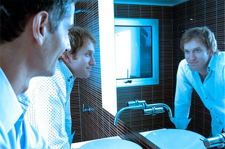 Men looking at mirror in washroom, smiling Stock Photo - Premium Royalty-Free, Code: 6108-05859493