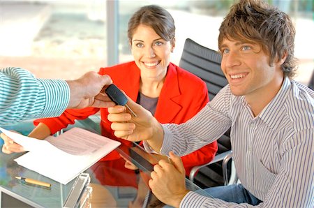 security desk - Car dealer handing car key to customer, smiling Stock Photo - Premium Royalty-Free, Code: 6108-05859423