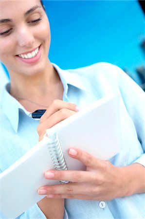 Businesswoman writing on notebook, smiling Stock Photo - Premium Royalty-Free, Code: 6108-05859438