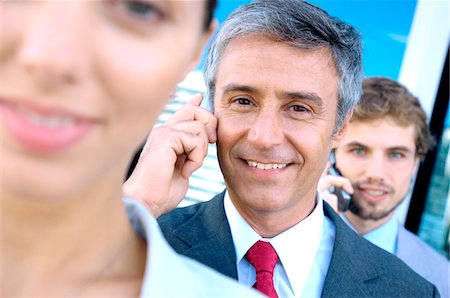 Business people using mobile phones, smiling Stock Photo - Premium Royalty-Free, Code: 6108-05859552