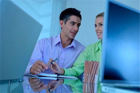 simsearch:6108-05859344,k - Businessman sitting with female colleague in office, smiling Stock Photo - Premium Royalty-Free, Code: 6108-05859568