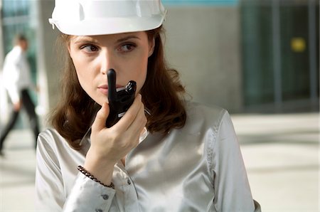 Close-up of a young woman talking on a walkie-talkie Stock Photo - Premium Royalty-Free, Code: 6108-05859696