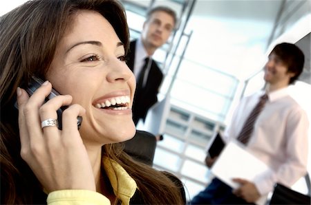 Businesswoman using mobile phone with colleagues in background Stock Photo - Premium Royalty-Free, Code: 6108-05859625