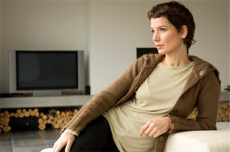 Mid adult woman leaning against a couch Stock Photo - Premium Royalty-Free, Code: 6108-05859751