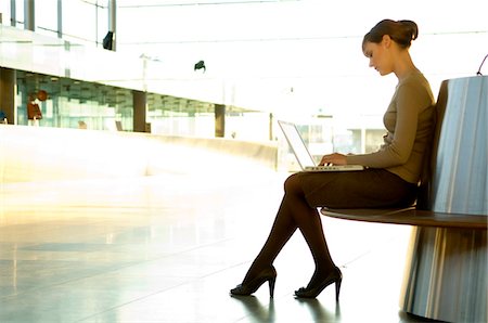 Profil de côté d'une femme d'affaires à l'aide d'un ordinateur portable à un salon de l'aéroport Photographie de stock - Premium Libres de Droits, Code: 6108-05859712