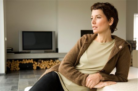 Mid adult woman leaning against a couch Stock Photo - Premium Royalty-Free, Code: 6108-05859946