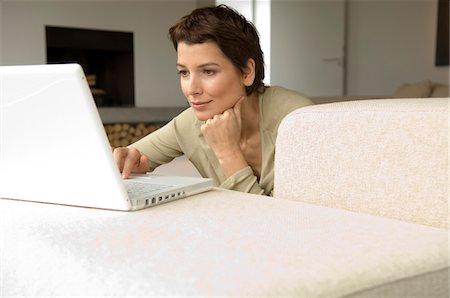 simsearch:6108-05861100,k - Mid adult woman working on a laptop in a living room Fotografie stock - Premium Royalty-Free, Codice: 6108-05859935