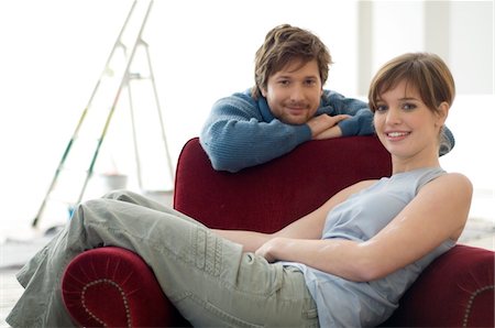 Young woman sitting in an armchair and a mid adult man leaning behind her Stock Photo - Premium Royalty-Free, Code: 6108-05860044