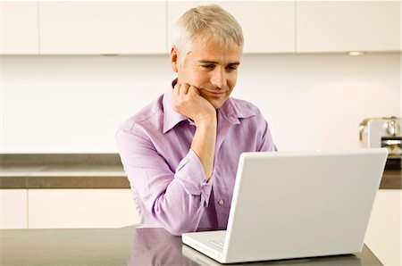 simsearch:6108-05860003,k - Mature man working on a laptop in the kitchen Stock Photo - Premium Royalty-Free, Code: 6108-05860012