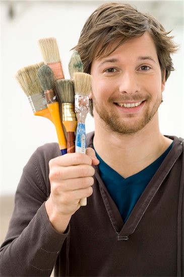 Portrait of a mid adult man holding paintbrushes Stock Photo - Premium Royalty-Free, Image code: 6108-05860032