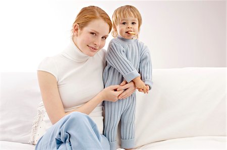 Portrait of a young woman sitting on a couch with her son Stock Photo - Premium Royalty-Free, Code: 6108-05860143