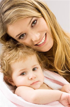 Portrait of a young woman wrapping her son in a towel and smiling Stock Photo - Premium Royalty-Free, Code: 6108-05860158