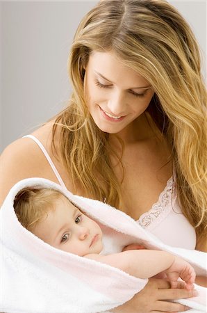 Close-up of a young woman wrapping her son in a towel and smiling Stock Photo - Premium Royalty-Free, Code: 6108-05860168