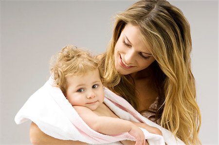 Close-up of a young woman wrapping her son in a towel and smiling Stock Photo - Premium Royalty-Free, Code: 6108-05860199