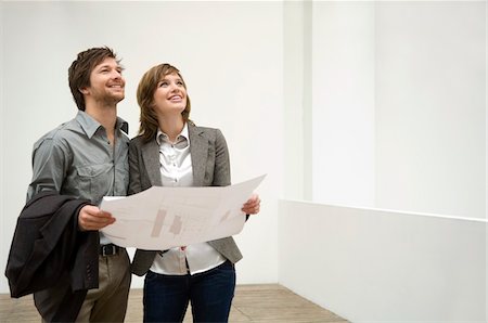 Mid adult man and a young woman holding a blueprint Stock Photo - Premium Royalty-Free, Code: 6108-05860134