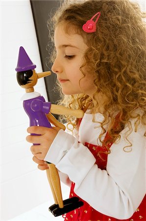 Side profile of a girl playing with a toy Foto de stock - Royalty Free Premium, Número: 6108-05860285