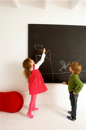 pizarra - Girl drawing on a blackboard and her brother watching her Foto de stock - Sin royalties Premium, Código: 6108-05860294
