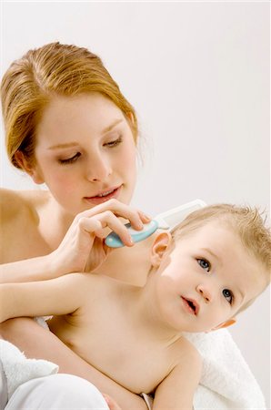 Close-up of a young woman combing hair of her son and smiling Stock Photo - Premium Royalty-Free, Code: 6108-05860211