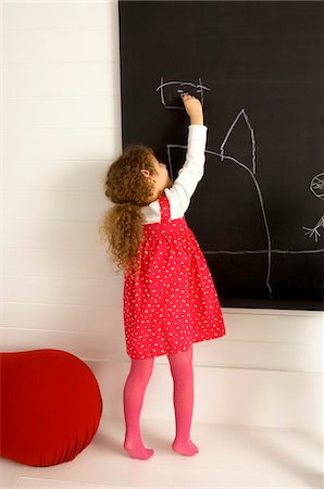 drawing on chalkboard - Girl drawing on a blackboard Stock Photo - Premium Royalty-Free, Code: 6108-05860226