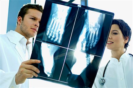 doctor looking at xray - Close-up of two doctors examining an X-Ray report Stock Photo - Premium Royalty-Free, Code: 6108-05860348