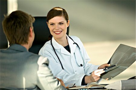 Female doctor showing an X-Ray report to a patient Stock Photo - Premium Royalty-Free, Code: 6108-05860369