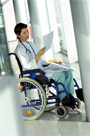 simsearch:6108-05860406,k - Female doctor sitting in a wheelchair and reading a medical record Fotografie stock - Premium Royalty-Free, Codice: 6108-05860370