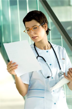 simsearch:6108-05860439,k - Female doctor reading medical records Stock Photo - Premium Royalty-Free, Code: 6108-05860374