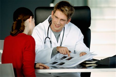 doctor at desk with patient - Male doctor explaining a medical record to a female patient Stock Photo - Premium Royalty-Free, Code: 6108-05860385