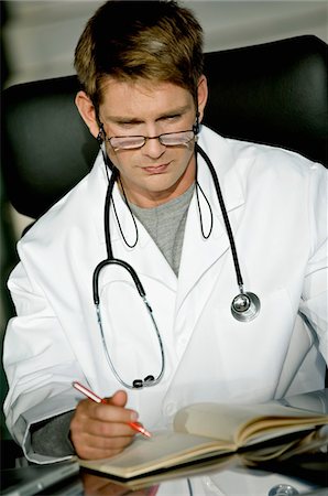 simsearch:6108-05860479,k - Nahaufnahme eines männlichen Arztes am Schreibtisch sitzen und lesen eine notebook Stockbilder - Premium RF Lizenzfrei, Bildnummer: 6108-05860395