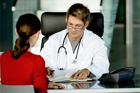 simsearch:6108-05860406,k - Male doctor sitting with a female patient and making notes in his office Fotografie stock - Premium Royalty-Free, Codice: 6108-05860317