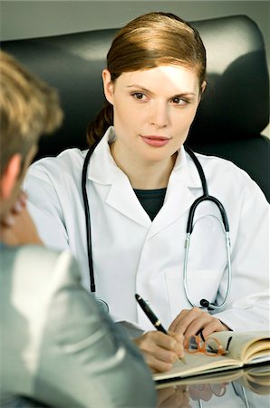 simsearch:6108-05860355,k - Female doctor sitting at a desk and talking with a patient Foto de stock - Sin royalties Premium, Código: 6108-05860316