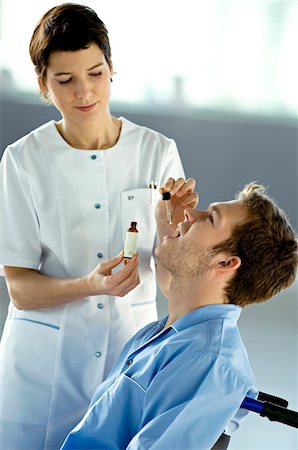 simsearch:6108-05860439,k - Female doctor giving medicine drops to a male patient Stock Photo - Premium Royalty-Free, Code: 6108-05860331