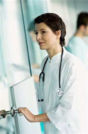 females opening doors - Side profile of a female doctor holding a door handle and smiling Stock Photo - Premium Royalty-Free, Code: 6108-05860336
